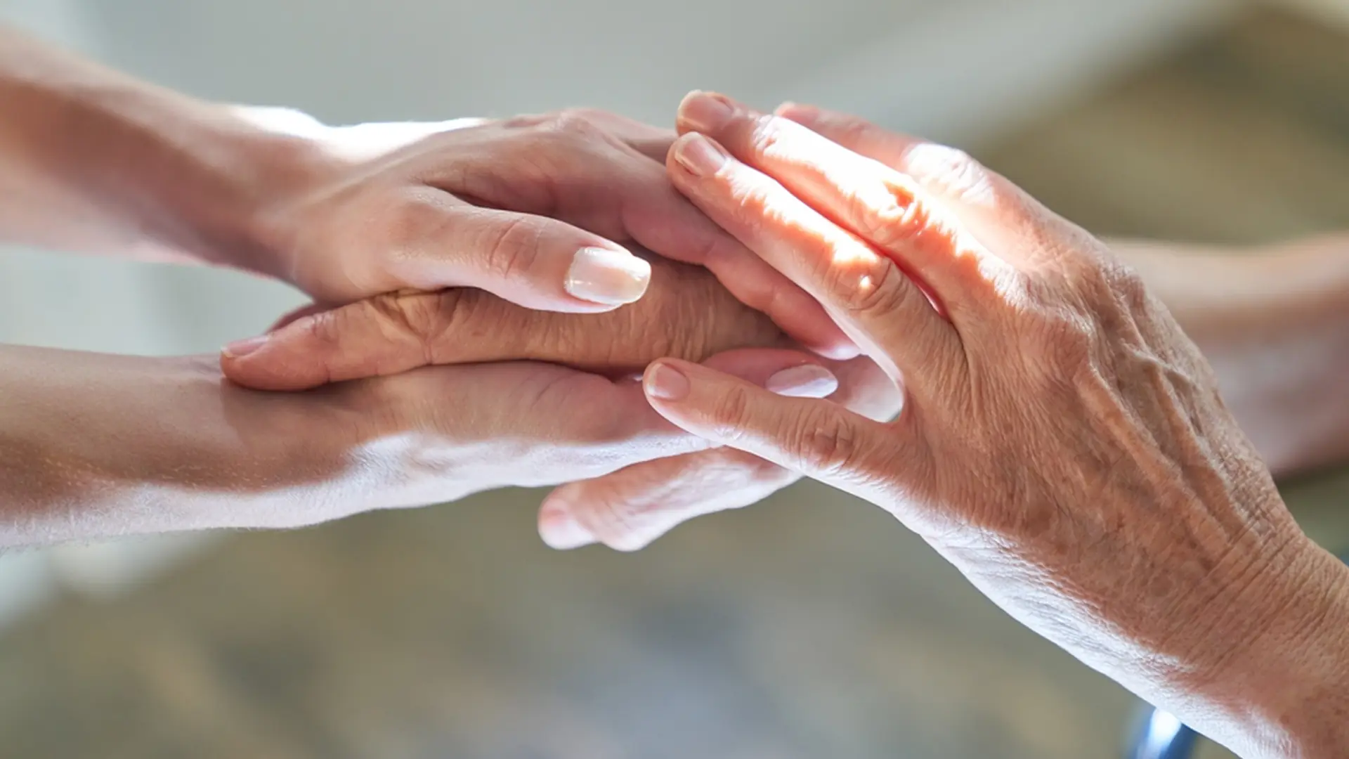 Symbolbild: Eine jüngere Hand hält behutsam die Hand eines älteren Menschen.