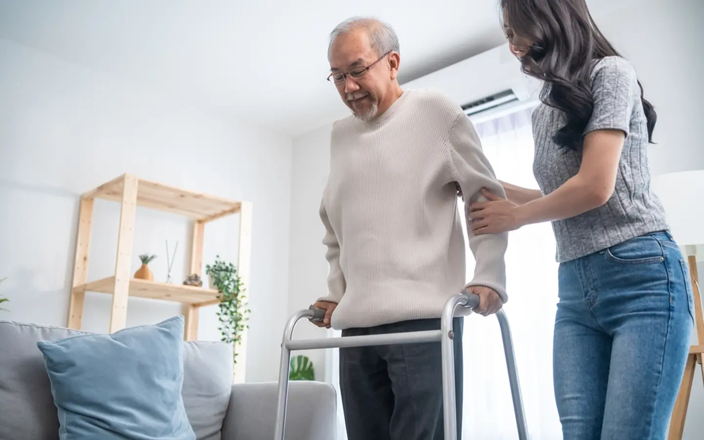 Symbolbild: Pflegekraft unterstützt einen älteren Mann am Rollator.